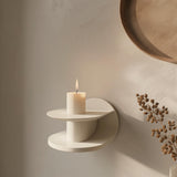 3D printed modern wall shelf in matte cream color, featuring a sculptural circular design with a candle displayed on top.