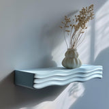 Wavy 3D printed wall shelf with a ripple-shaped support holding a decorative vase.