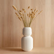 Tall 3D printed white geometric vase with ribbed texture, holding dried grass stems.