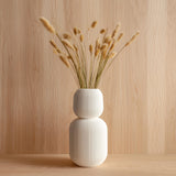 Tall 3D printed white geometric vase with ribbed texture, holding dried grass stems.