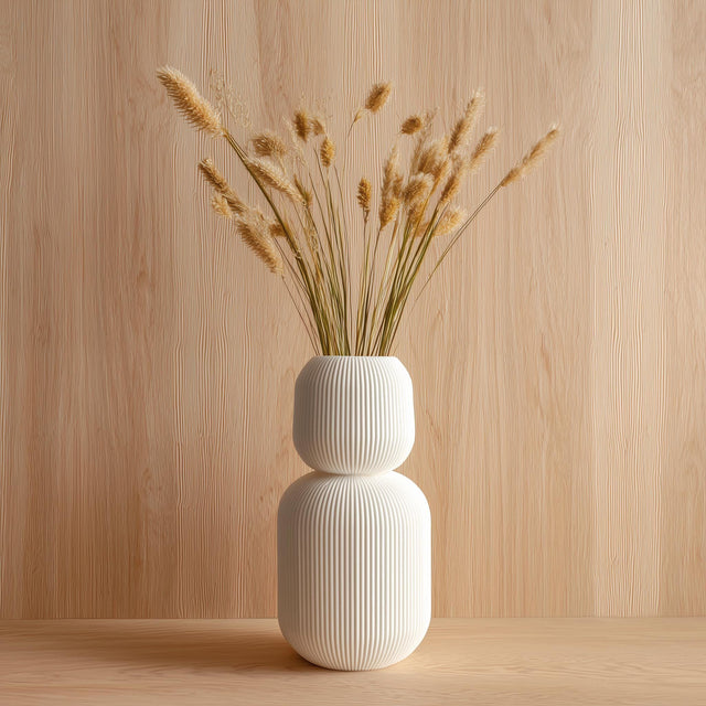 Tall 3D printed white geometric vase with ribbed texture, holding dried grass stems.