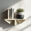 Cream geometric 3D printed wall shelf holding lightweight books and a potted plant.