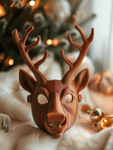 3D printed reindeer mask with sculptural antlers placed near a decorated Christmas tree.