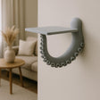 A sculptural 3D printed wall shelf designed to resemble a curled octopus tentacle with suction cups.