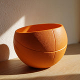 Orange 3D printed bowl shaped like a sliced basketball made from matte PLA.