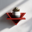 Triangular 3D printed altar wall shelf holding a small potted plant.