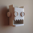 White 3D printed robot head wall organizer with an open mouth storage niche.