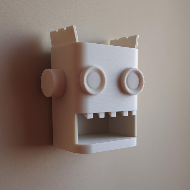 White 3D printed robot head wall organizer with an open mouth storage niche.