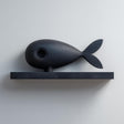 3D printed matte PLA wall shelf with a stylized fish figure resting on a slim rectangular ledge.