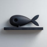 3D printed matte PLA wall shelf with a stylized fish figure resting on a slim rectangular ledge.