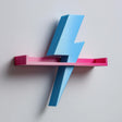 3D printed wall shelf shaped like a lightning bolt passing through a slim tray-style ledge.