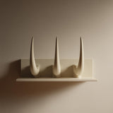 3D printed wall-mounted shelf with three tall curved horns rising from a back panel in matte PLA.