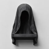 3D printed matte black wall shelf shaped like a hooded cloaked figure with a dark empty face and a small ledge at the bottom.