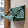 3D printed matte green wall shelf with integrated chain supports.