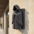 3D printed wall-mounted hooded figure with deep cloak folds and a faceless dark interior.