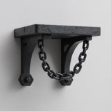 3D printed matte black wall shelf with two curved brackets connected by a decorative hanging chain.