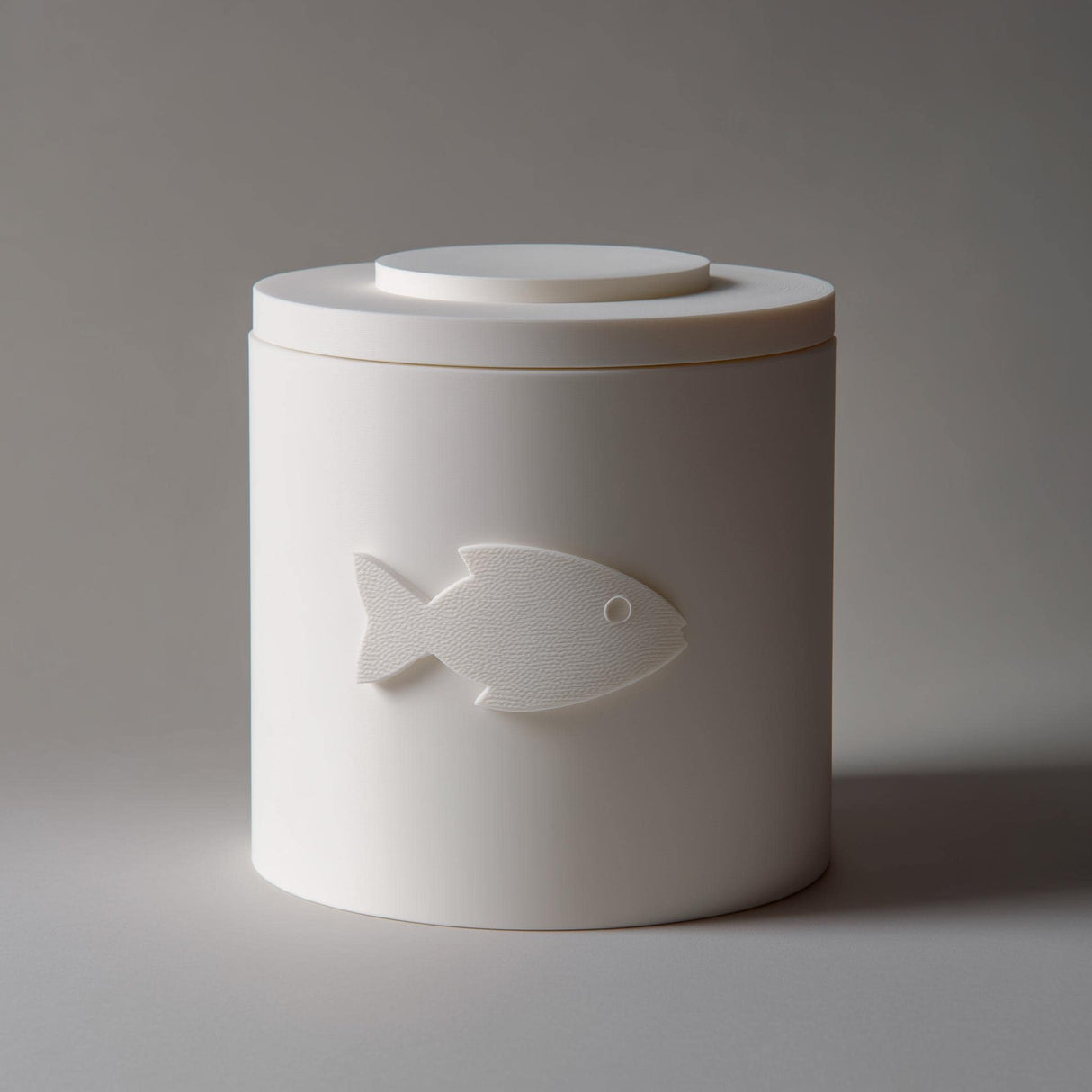 3D printed minimalist cylindrical pet ashes urn with a raised fish emblem on the front and a fitted lid.