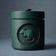 3D printed minimalist cylindrical pet ashes urn with a raised mouse medallion on the front and a fitted lidded top.