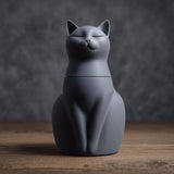 3D printed minimalist cat-shaped pet ashes urn with closed eyes and a fitted lid seam and visible print texture.