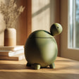 3D printed turtle-shaped pet ashes urn in matte olive green PLA with visible print texture.