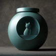 3D printed orb-shaped pet ashes urn with a circular recessed window featuring a small cat figure inside.