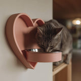 3D printed heart-shaped wall mounted pet bowl holder with a round bowl opening.