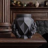 3D printed dark fantasy memorial urn with faceted geometric body and sculptural claw base displayed on a dark wooden mantel.