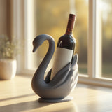 3D printed swan wine bottle holder in matte PLA holding a standard wine bottle near a sunny window.