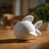 3D printed fish memorial urn with removable lid displayed on a wooden table in warm indoor lighting.