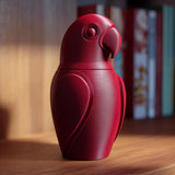 3D printed parrot memorial urn with removable lid displayed on a wooden shelf in warm indoor lighting.