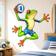 Bright green cartoon frog in blue floral shorts jumping while holding a blue-and-white volleyball.