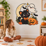 Young girl sitting on a rug looking at a Halloween cat and ghost wall sticker.