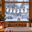 White vinyl window garland with six hanging Christmas stocking silhouettes on a gently curved line above a kitchen sink.