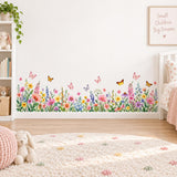 Watercolor wildflower wall border with colorful meadow blossoms, green leaves and butterflies along the base of a wall.
