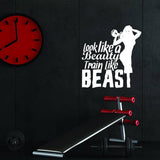 Motivational fitness wall decal saying 'look like a beauty train like a beast' in a gym setting.