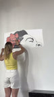 Woman applying a singing woman street-art wall decal with a flower design.