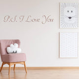 Romantic wall decal with 'P.S. I Love You' text above a pink chair and framed art.