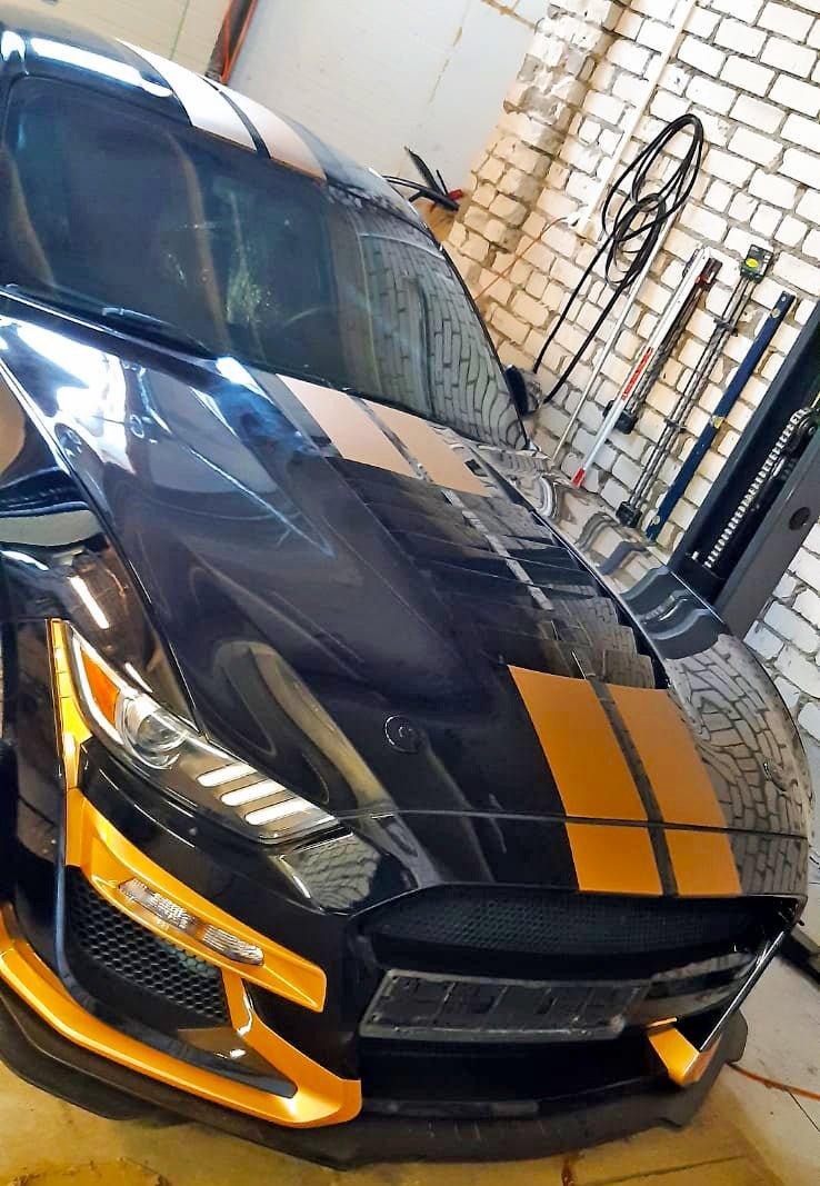 Оранжевые гоночные полосы на чёрном автомобиле в гараже.