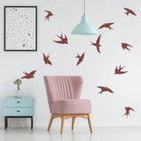 Bird themed wall decals in a cozy room with a pink chair and artistic wall art.