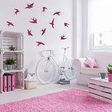 Flock of bird wall decals in a stylish living room with a bicycle and pink decor.