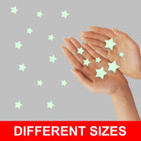 Hands showcasing various sizes of glow-in-the-dark star stickers for children's room decor.