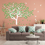 Serenity Tree Wall Sticker with green leaves on a peach wall, enhancing a cozy living room decor.