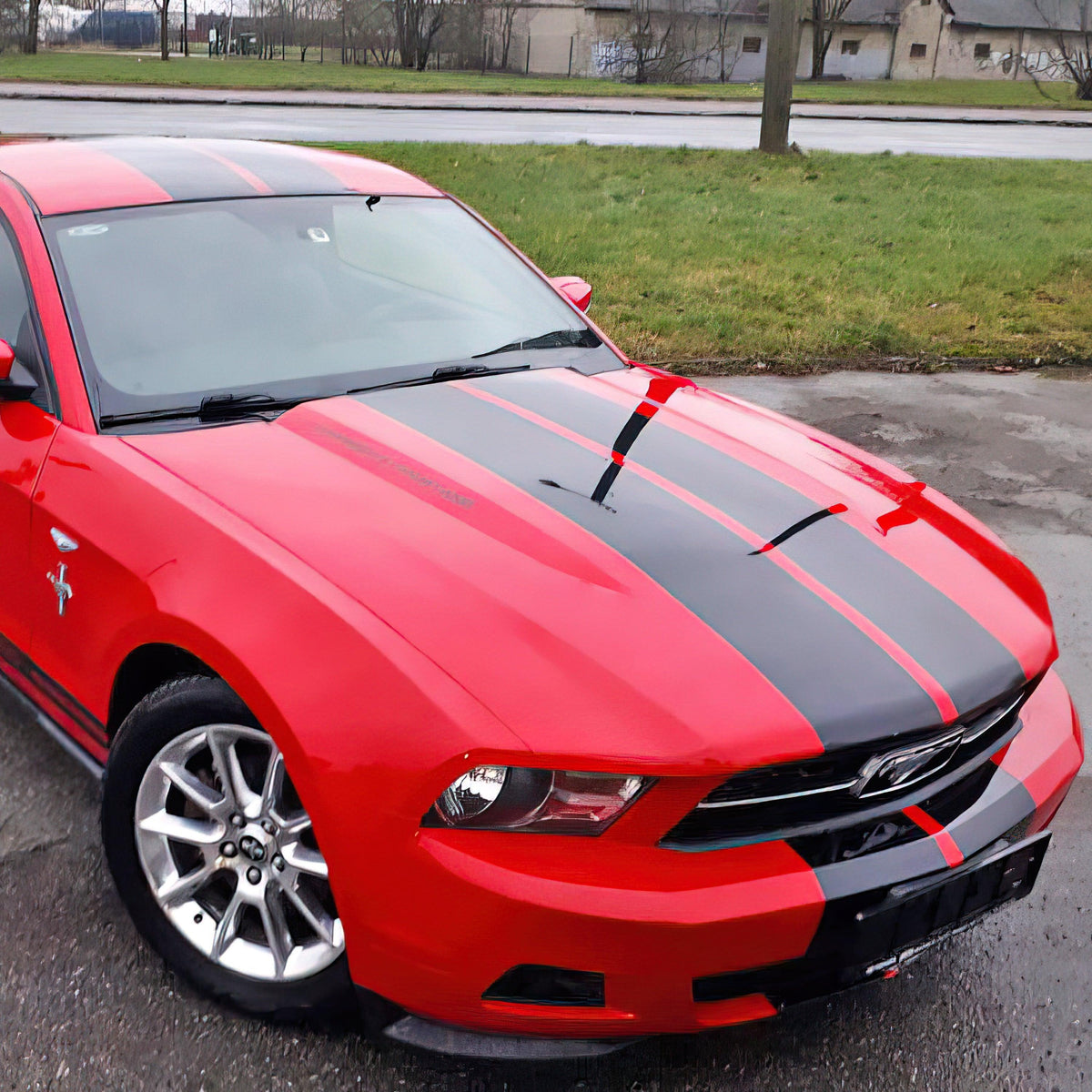 Stylish red car with black racing stripes showcasing vibrant vinyl decals for car upgrades.