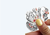 Hand holding vinyl anatomy stickers featuring heart, brain, and floral designs for Hydroflask decoration.