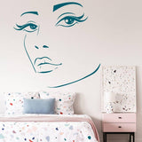 Charming woman face vinyl wall decal above a colorful bed.