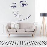 Charming woman face wall decal above a stylish sofa in a modern living room, adding artistic flair to interior design.