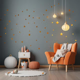 Cozy room featuring gold star vinyl wall stickers, an orange chair, and stylish decor accents.