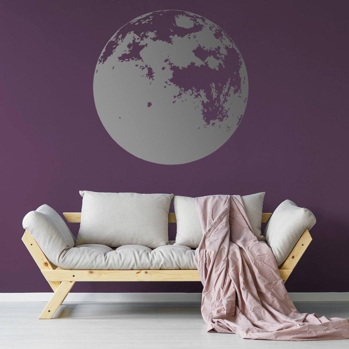 Moon phase wall decal on a dark purple wall with a cozy sofa and blanket.
