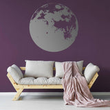 Moon phase wall decal on a dark purple wall with a cozy sofa and blanket.