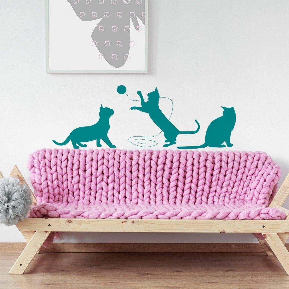 Adorable cat silhouette vinyl decal featuring playful cats on a pink knitted sofa.
